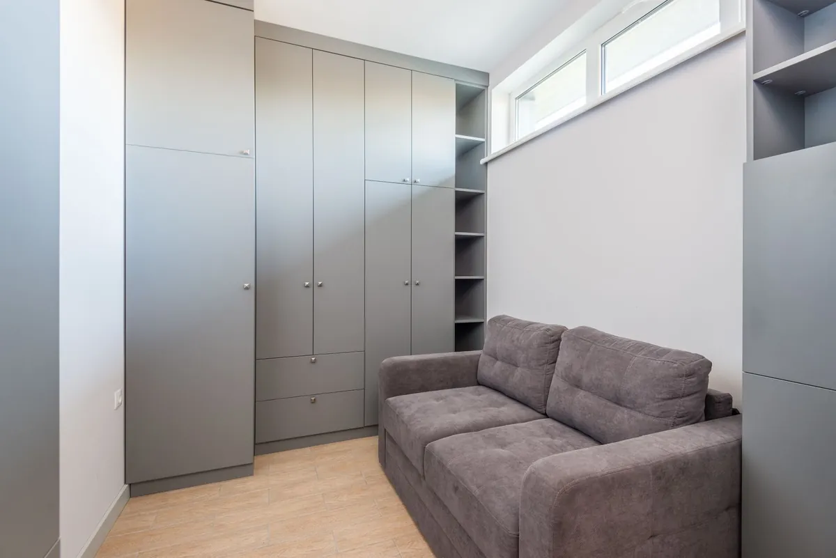 A small furnished unit with a sofa and a wardrobe, ready to let