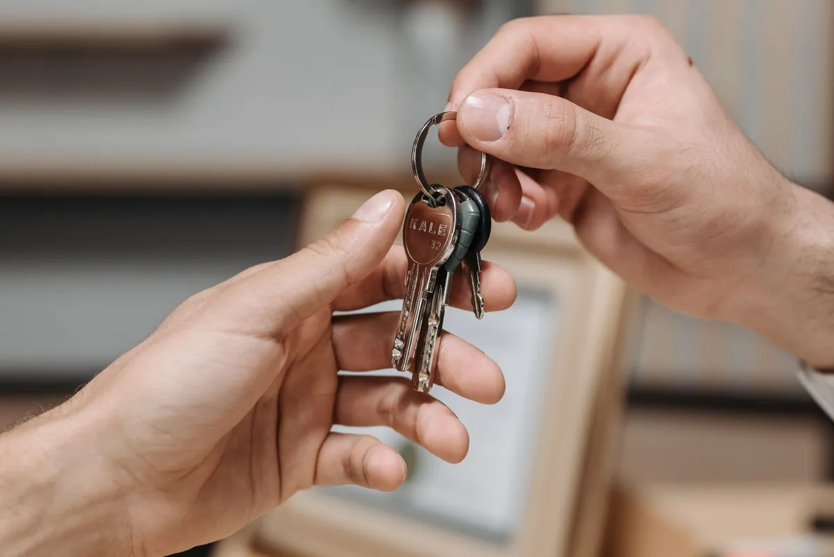 Two hands exchanging a set of keys indoors, close up