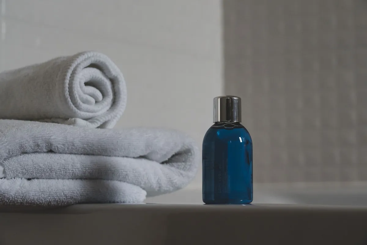 Folded towels and a small bottle on a pale bathroom counter