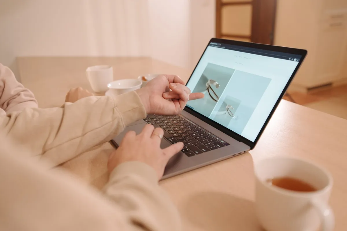 A person working on a laptop at a light table with a cup of tea beside it