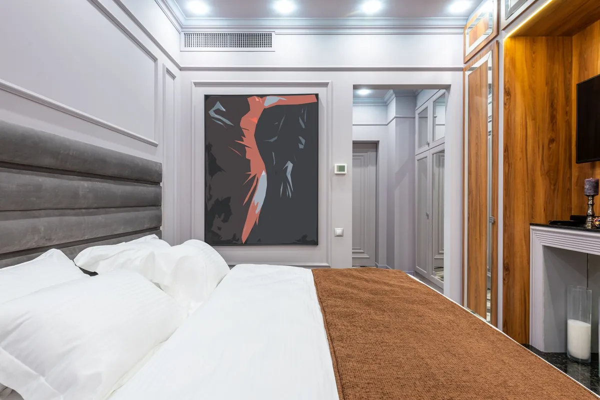 A contemporary hotel room with a made bed and a framed artwork