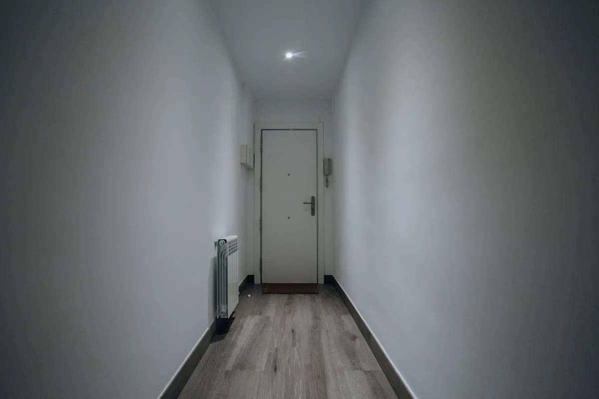 A narrow grey hallway ending at a closed apartment door