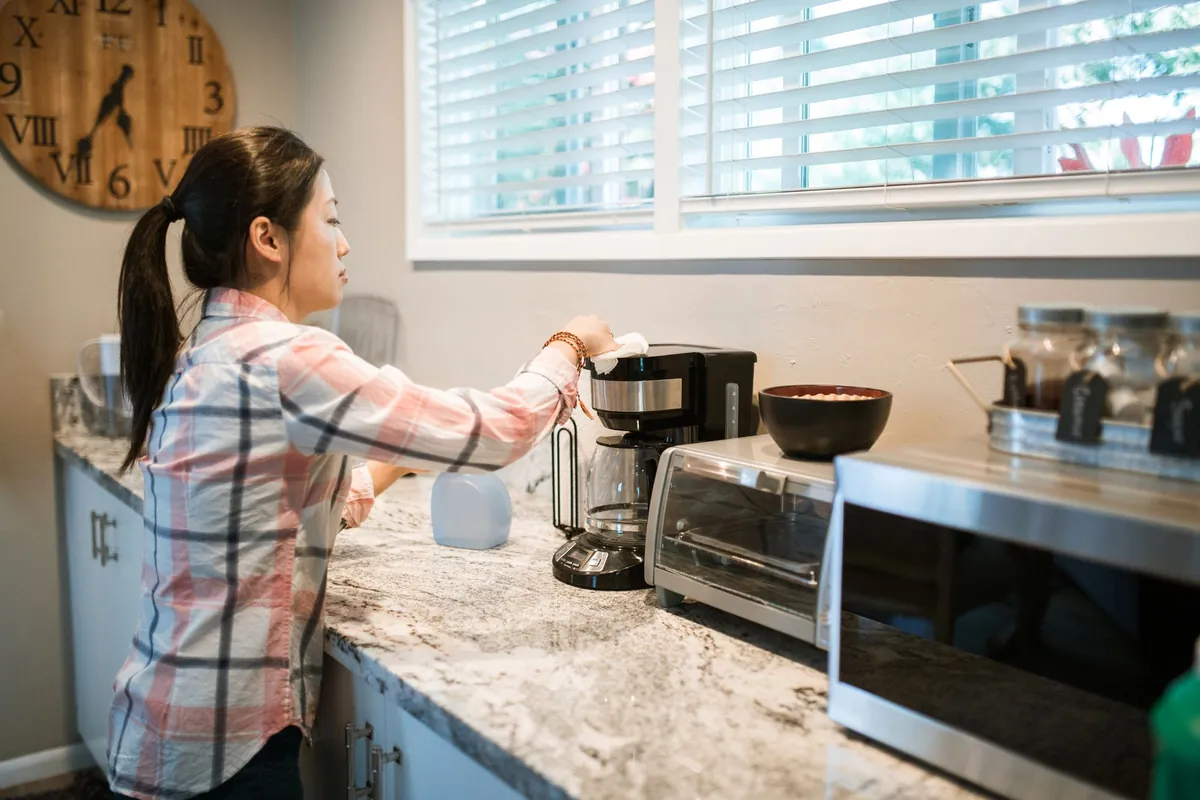 Woman cleaning a coffee maker in a bright modern kitchen