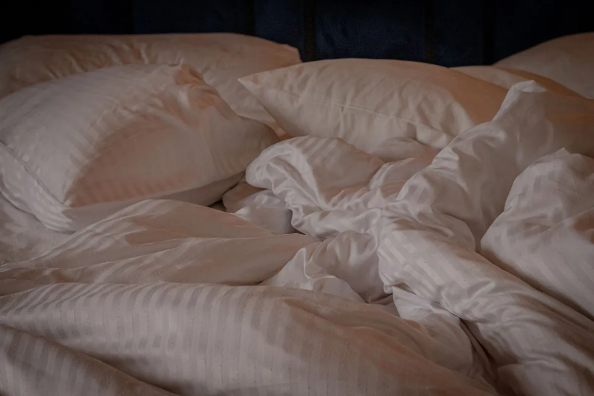 An unmade bed with rumpled white sheets and pillows after a guest checkout