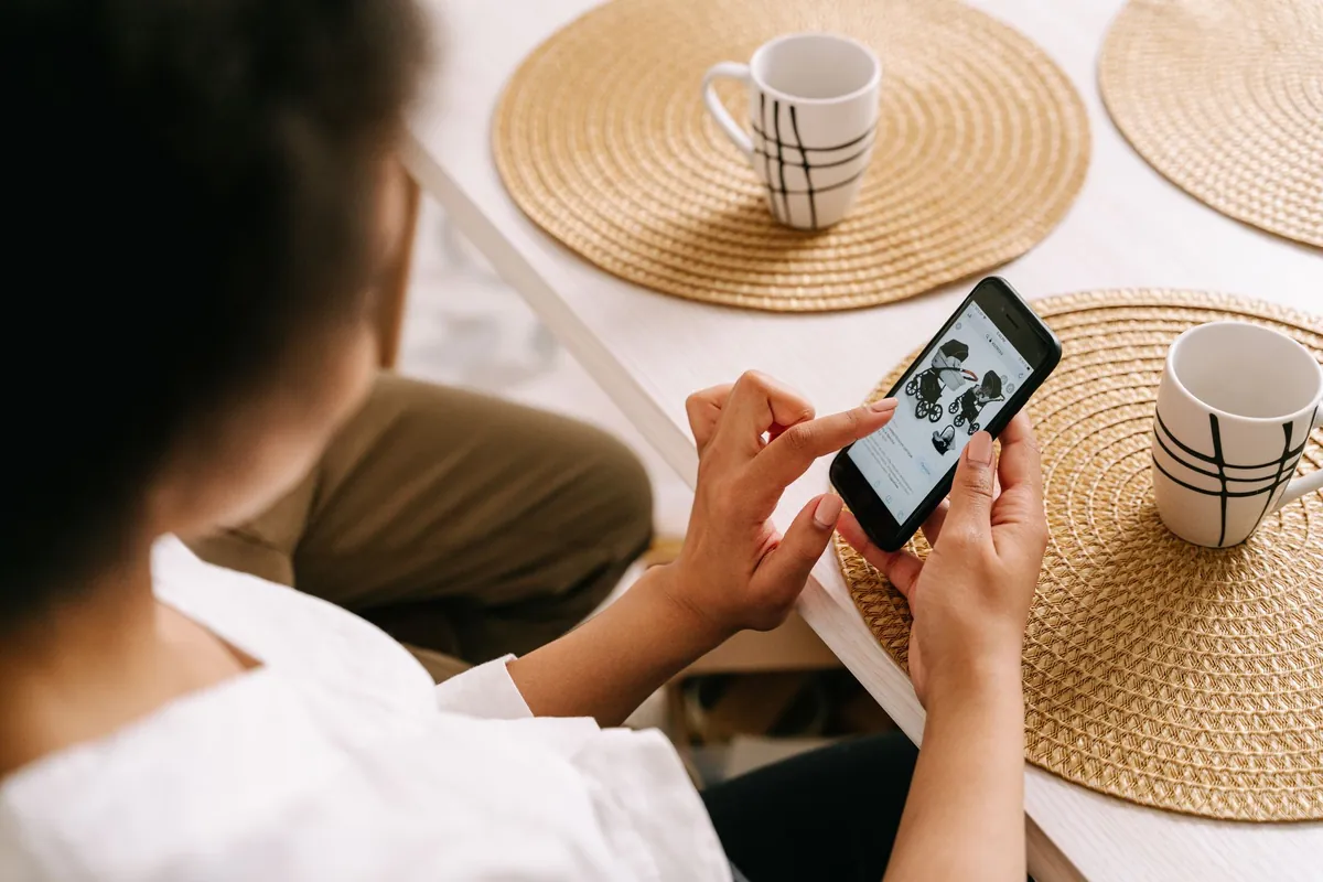 Hands holding a phone over a table with woven placemats and coffee cups