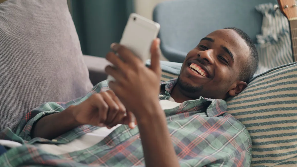 Young man relaxing at home on a couch while using a smartphone