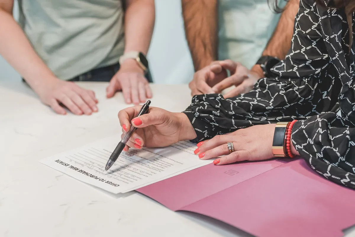 Hands signing a real estate document on a meeting table