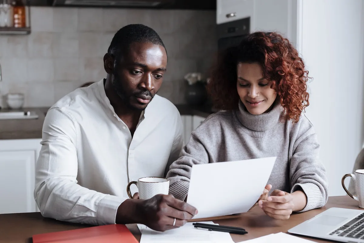 Two people sitting at a kitchen table reviewing paperwork together