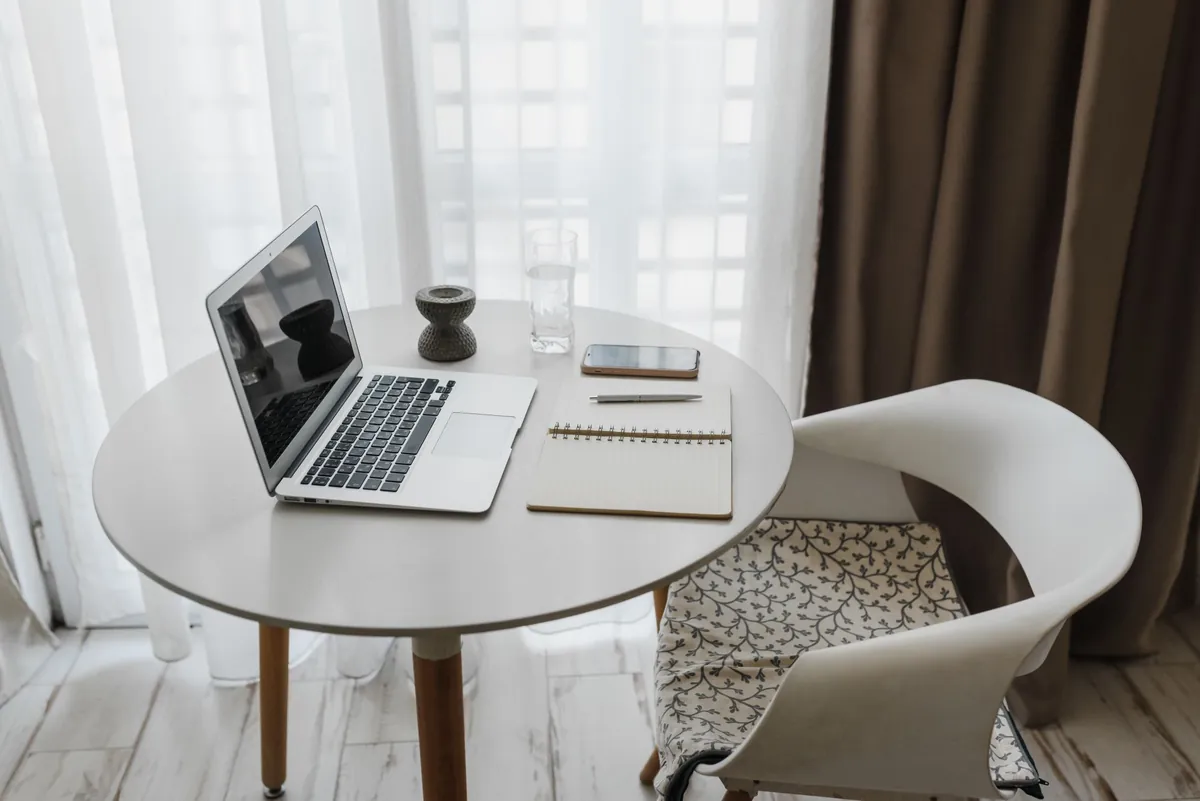 Laptop, notebook, and smartphone arranged on a round table in a home office