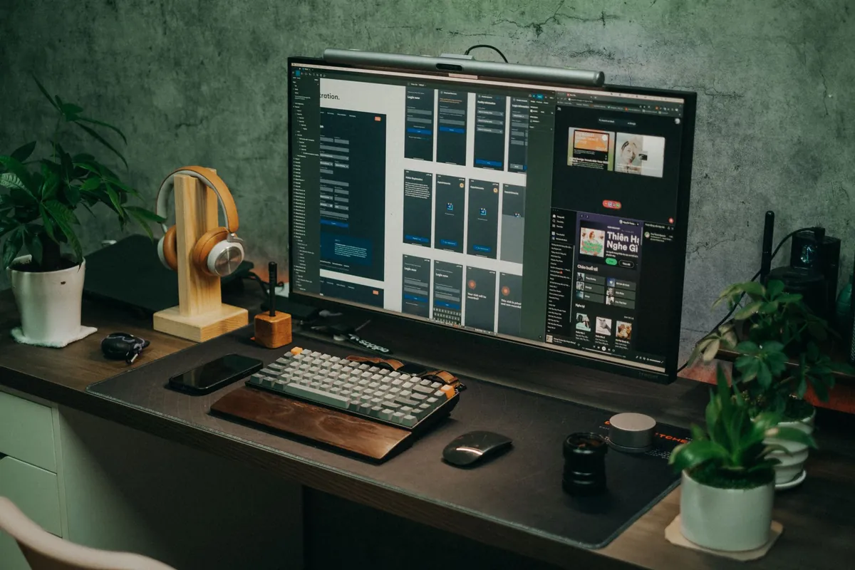 Laptop, smartphone, and headphones arranged on a dark desk workspace
