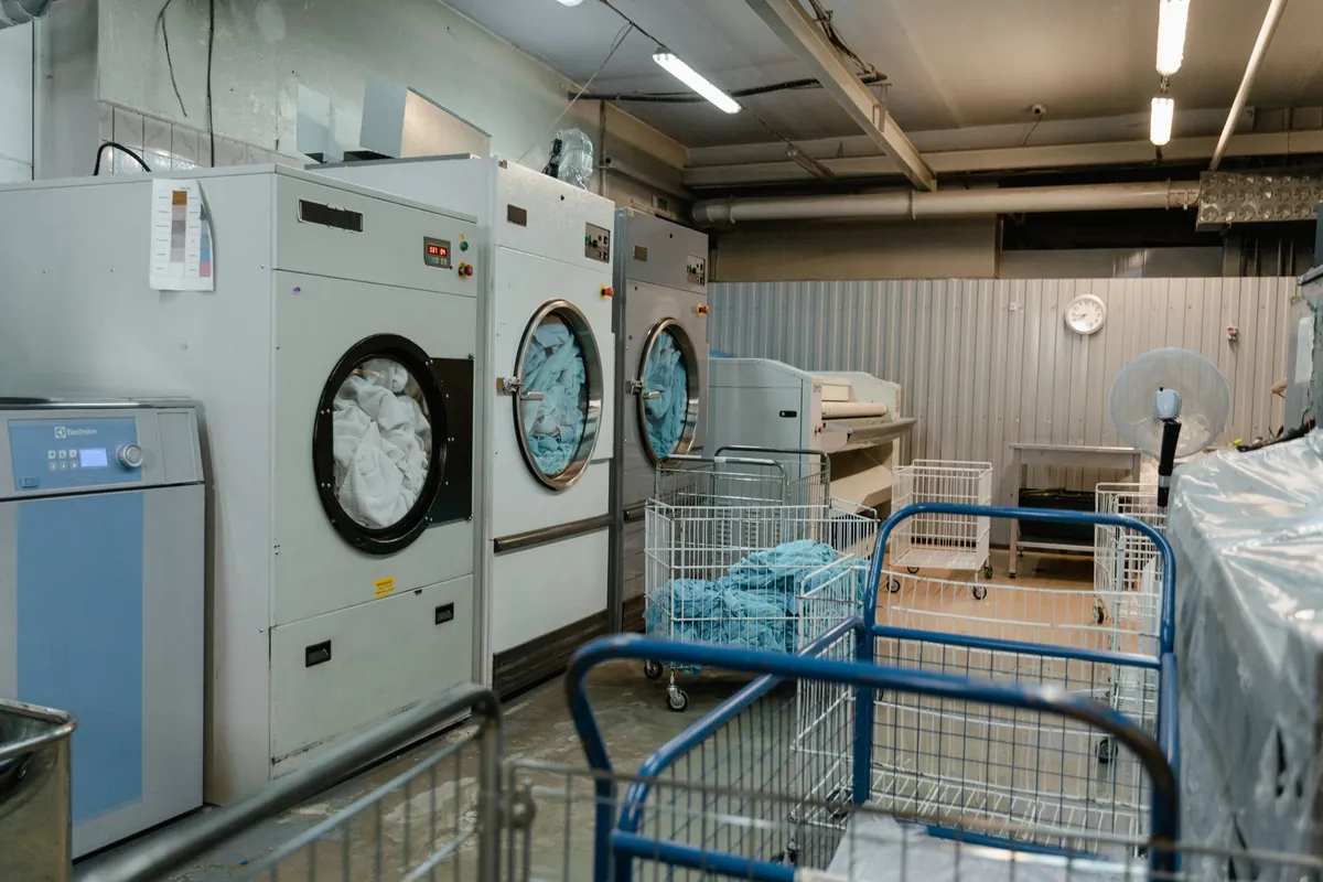 Laundry room with washing machines, carts, and stacks of folded linens