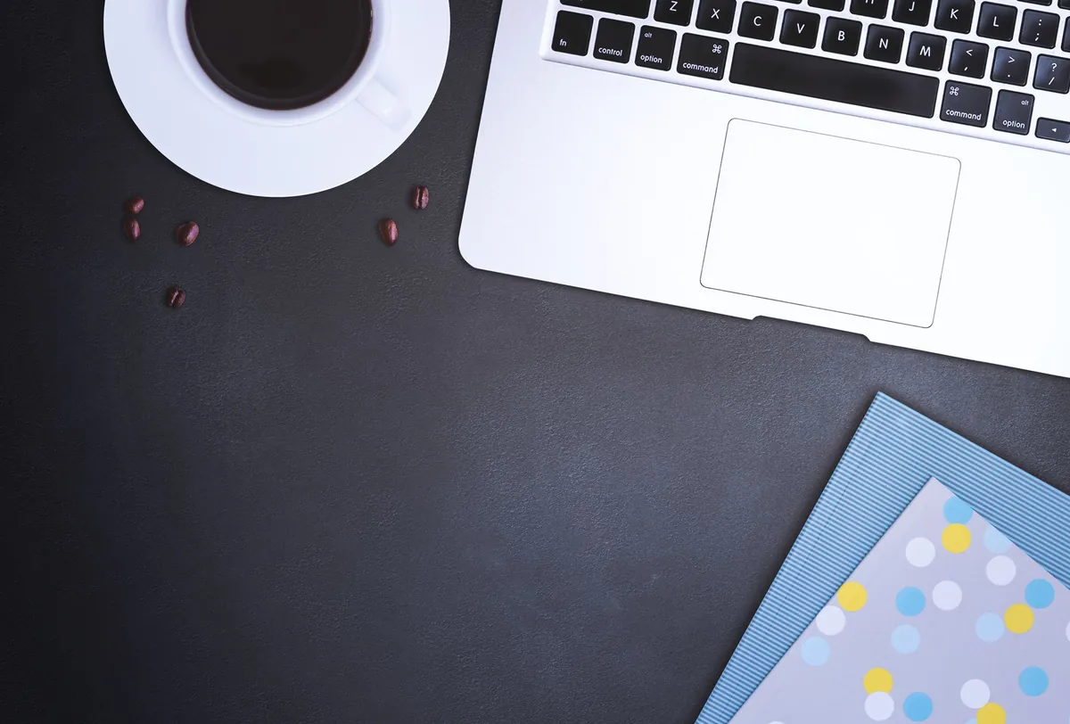 Flat lay of a desk with a laptop, coffee cup, and printed documents