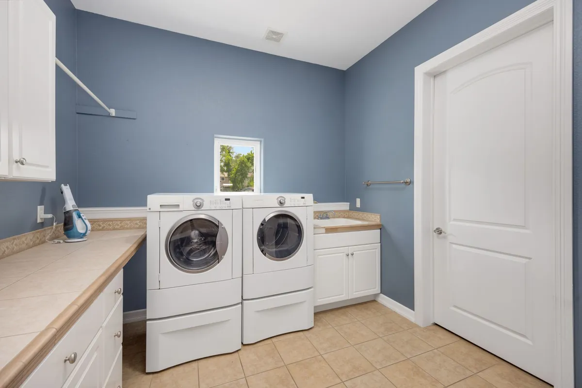 Spacious laundry room with modern washing machines and storage cabinets