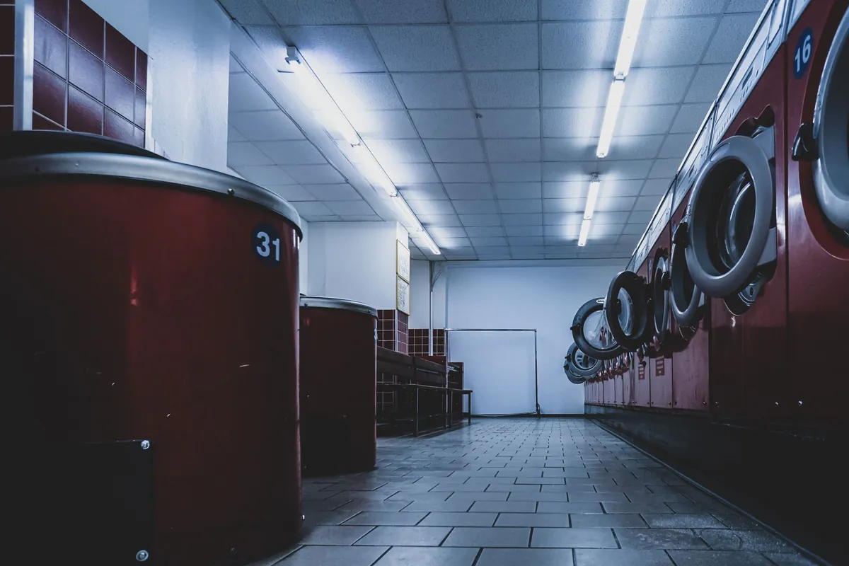 Rows of white washing machines inside a laundromat.
