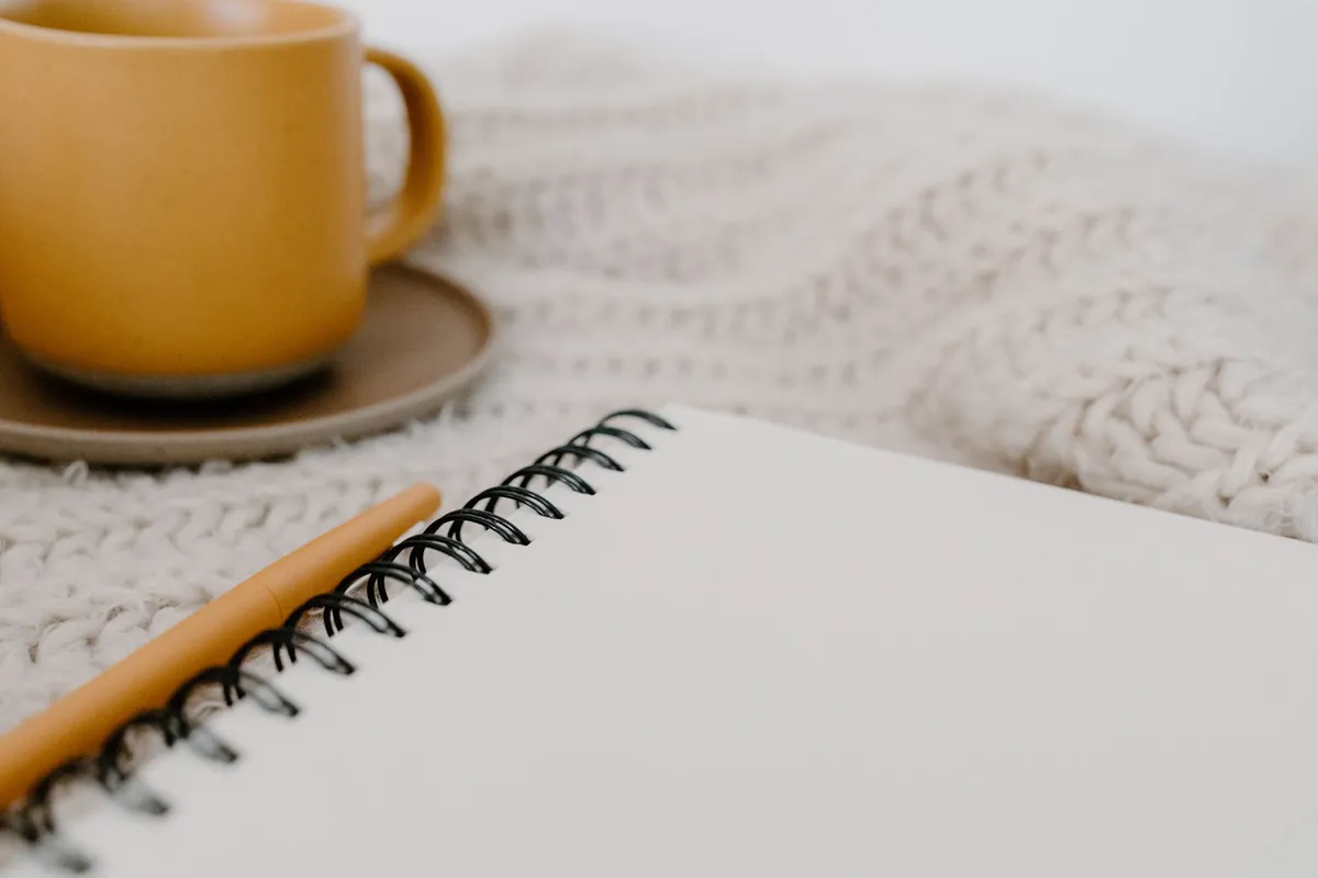 Blank spiral notebook and pen on a desk beside a coffee mug