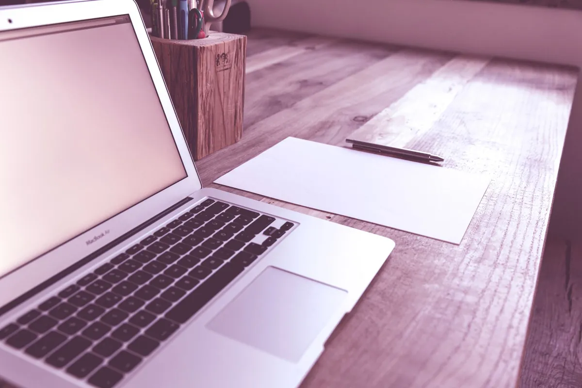Laptop, papers, and a pen arranged on a tidy desk