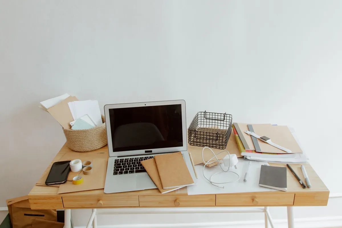 Tidy desk with a laptop, notebooks, and office supplies arranged neatly