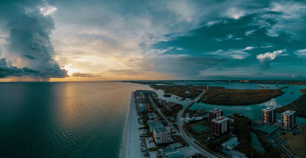 Aerial view of a Florida coastline at sunset with dramatic clouds over the water