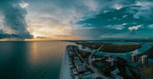 Aerial view of a Florida coastline at sunset with dramatic clouds over the water