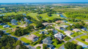 Aerial view of a sunny suburban neighborhood with green lawns and houses with solar panels