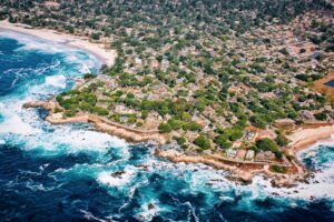 Rocky shoreline along a coastal town with blue ocean water under a clear sky.