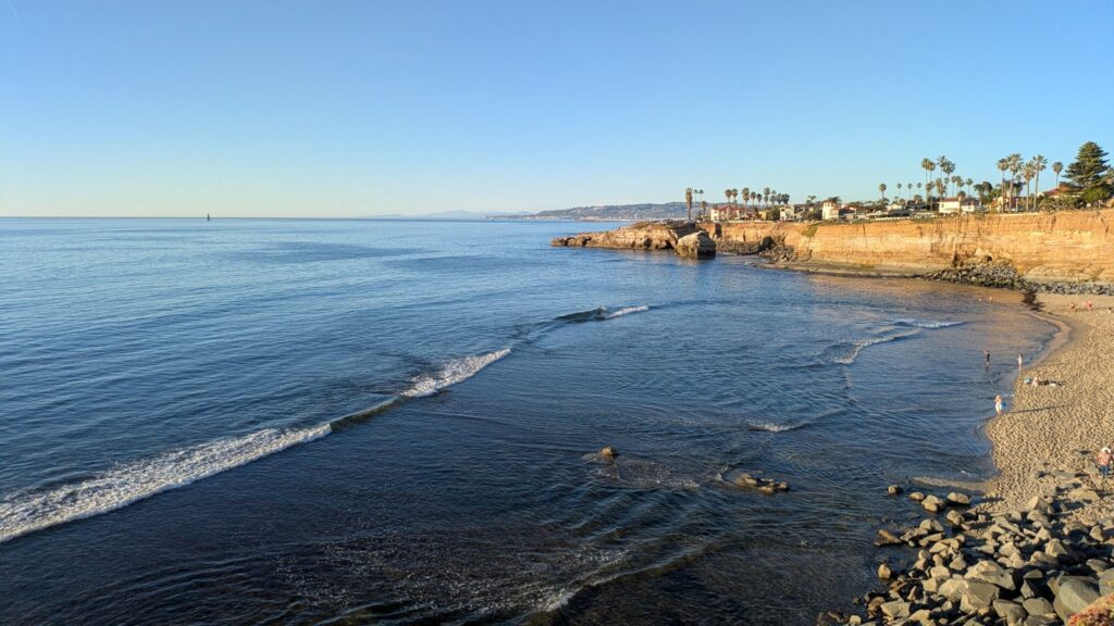 Pacific Ocean waves meeting a rocky shore at Sunset Cliffs with a low coastal wall