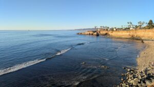 Pacific Ocean waves meeting a rocky shore at Sunset Cliffs with a low coastal wall