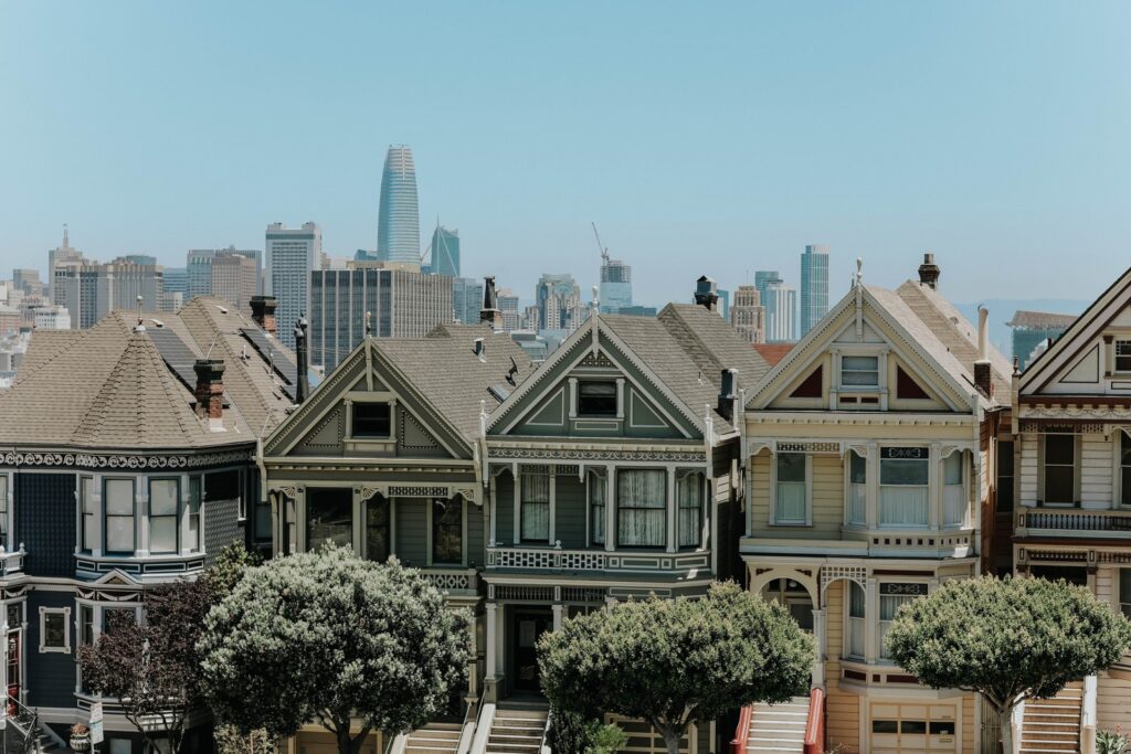 Colorful Victorian row houses on a San Francisco hill with the city skyline behind them