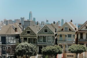 Colorful Victorian row houses on a San Francisco hill with the city skyline behind them
