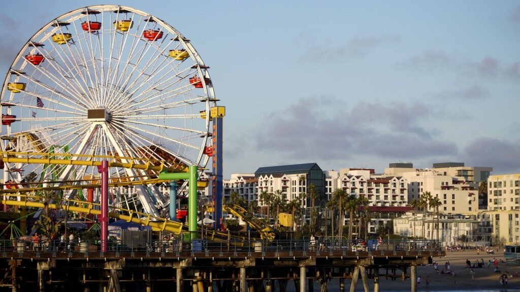 Ferris wheel on a seaside pier with beachfront buildings behind it