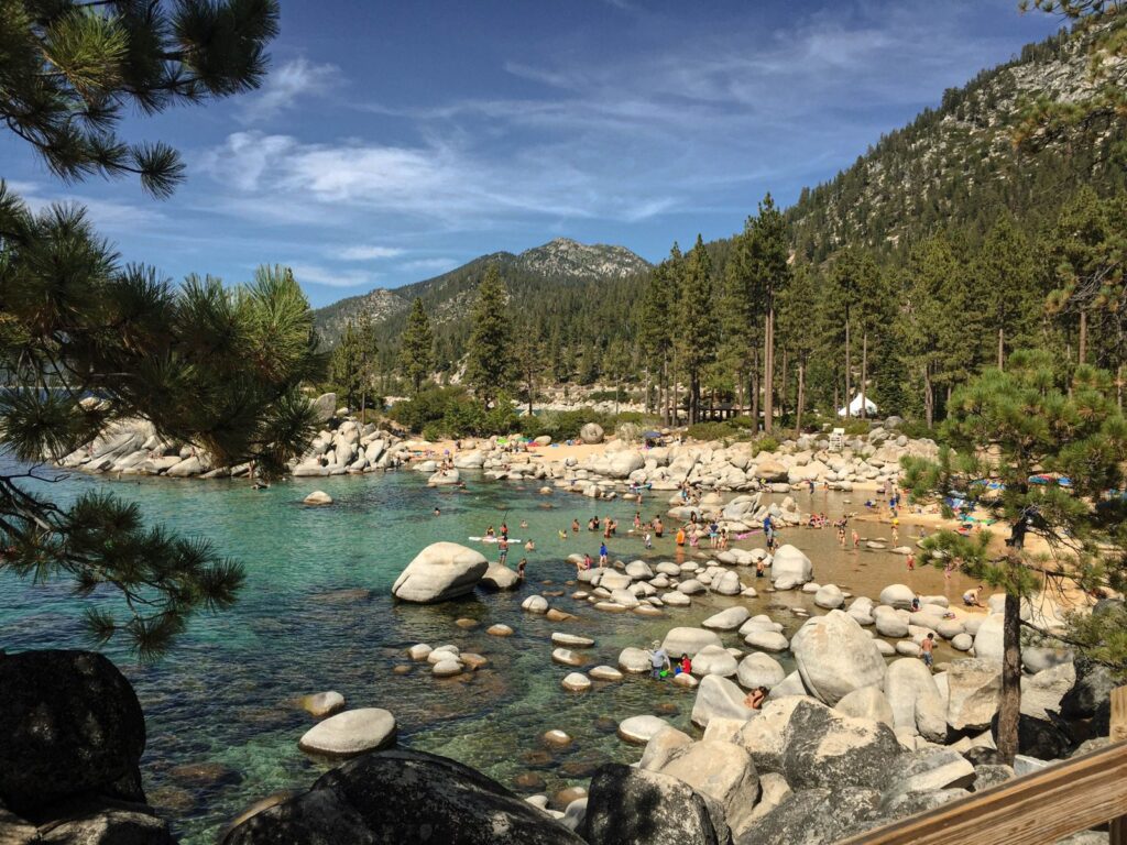 Mountain lake with clear water, pine trees and snowy peaks along the shore