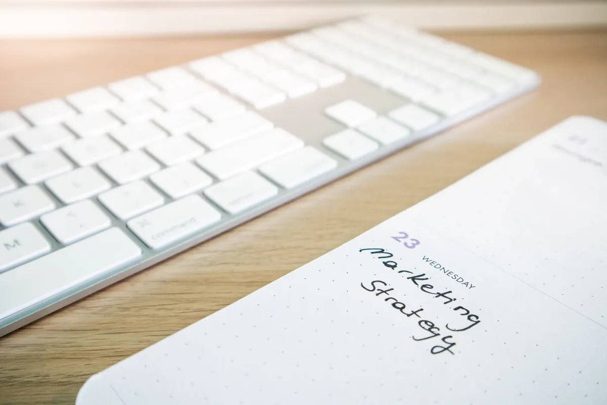 Open notebook with handwritten notes beside a keyboard on a wooden desk