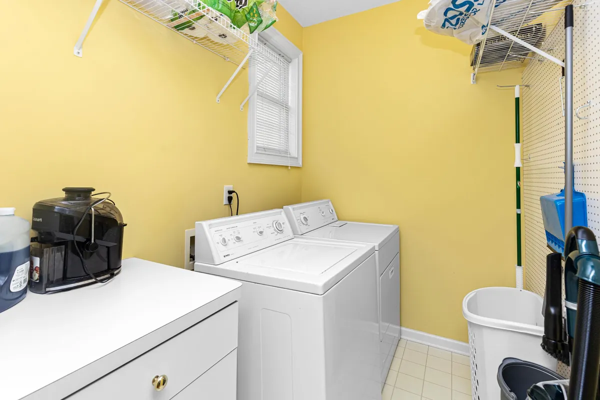 Bright laundry room with a washer, dryer and storage shelves