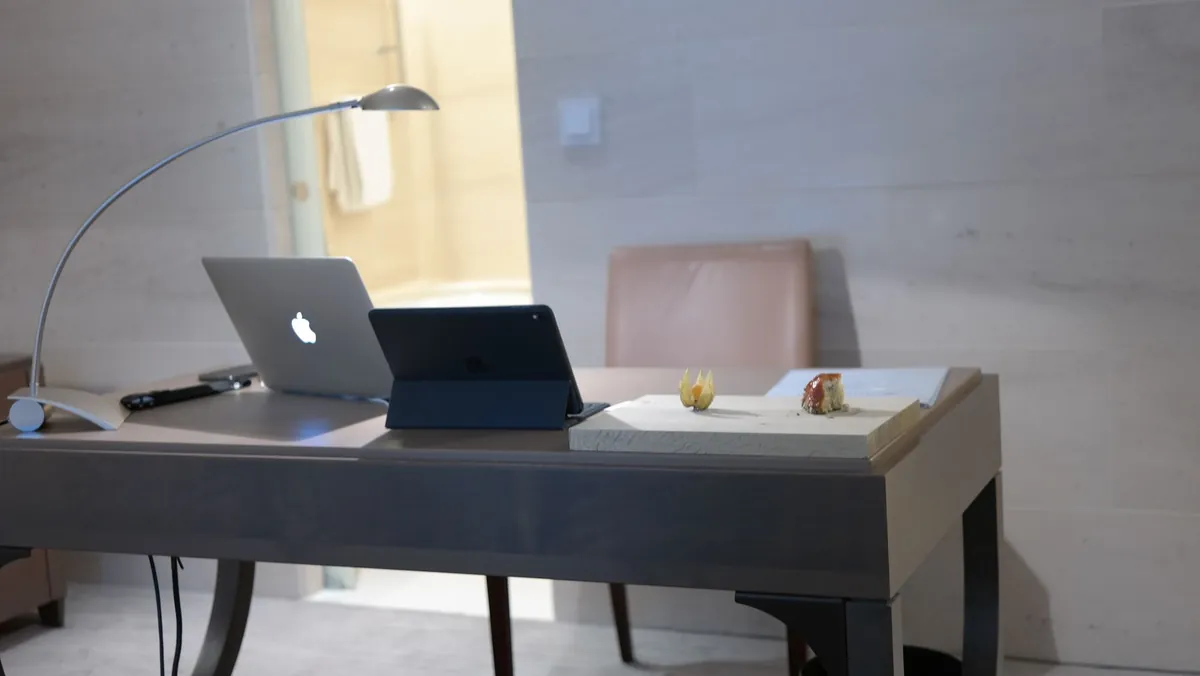 Laptop and tablet sitting on a wooden desk in a home office