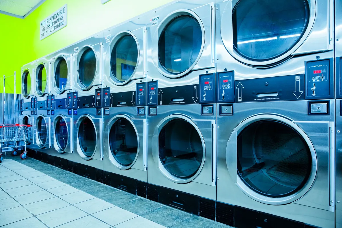 Rows of clean white washing machines in a bright laundromat